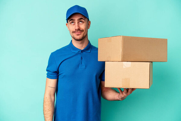 Молодой поставщик кавказский человек на голубом фоне мечтает о достижении целей и задач