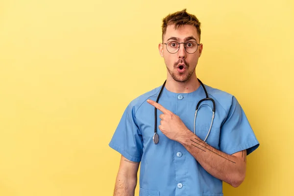 Jonge Verpleegster Blanke Man Geïsoleerd Gele Achtergrond Wijzend Naar Zijkant — Stockfoto