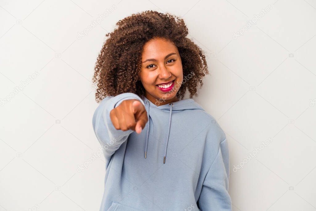 Young african american woman with curly hair isolated on white background cheerful smiles pointing to front.