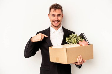 Beyaz arka planda izole edilmiş beyaz tenli genç beyaz iş adamı, gururlu ve kendinden emin bir şekilde gömlek fotokopi alanını işaret ediyor.