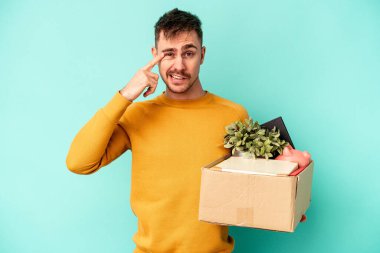 Kafkasyalı genç adam mavi arka planda izole bir hareket yapıyor işaret parmağıyla hayal kırıklığı jesti gösteriyor..