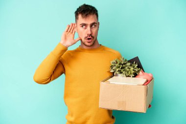 Kafkasyalı genç bir adam mavi arka planda bir dedikodu dinlemeye çalışıyor..