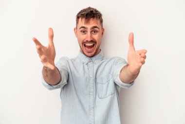 Beyaz arka planda izole edilmiş genç beyaz bir adam sorgulama sırasında omuz silkiyor ve şüphe duyuyor..