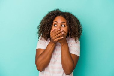 Mavi arka planda izole edilmiş kıvırcık saçlı, Afro-Amerikalı genç bir kadın. Ağzını eliyle kapatan bir fotokopi odasına özenle bakıyor..