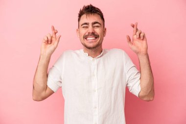 Pembe arka planda izole edilmiş beyaz bir adam şans getirsin diye dua ediyor.