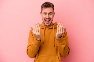 Pembe arka planda izole edilmiş genç beyaz adam sanki seni davet ediyormuş gibi seni işaret ediyor..