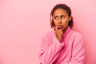 Pembe arka plan izole edilmiş bornoz giyen genç Afrikalı Amerikalı kadın bir şeyin fotokopi odasına baktığını düşünerek rahatladı..