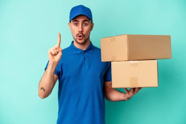 Genç teslimatçı beyaz adam mavi arka planda izole edilmiş. Harika bir fikri var, yaratıcılık kavramı..