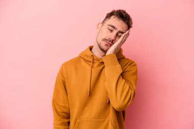 Pembe arka planda izole edilmiş genç beyaz adam sıkılmış, yorgun ve dinlenmeye ihtiyacı var..