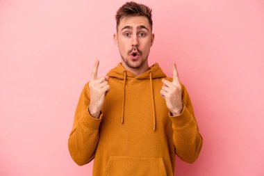 Pembe arka planda izole edilmiş beyaz bir adam ağzı açık bir şekilde üst tarafı işaret ediyor..