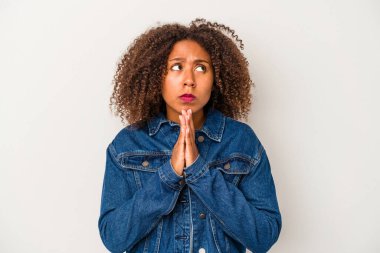 Beyaz arka planda izole edilmiş kıvırcık saçlı genç Afrikalı Amerikalı kadın dua ediyor, kendini adamış, kutsal ilhamı arayan dindar biri..