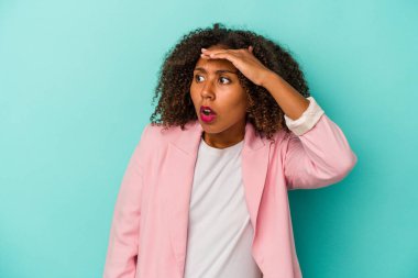 Mavi arka planda yalıtılmış kıvırcık saçlı, genç Afro-Amerikalı kadın. Uzağa bakıyor. Alnını tutuyor..
