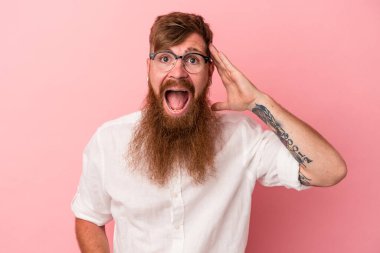 Pembe arka planda izole edilmiş uzun sakallı beyaz genç adam yüksek sesle bağırıyor, gözleri açık ve elleri gergin tutuyor..