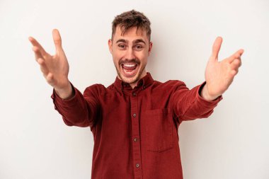 Beyaz arka planda izole edilmiş genç beyaz bir adam sorgulama sırasında omuz silkiyor ve şüphe duyuyor..