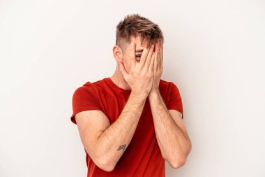 Beyaz arka planda izole edilmiş genç beyaz bir adam şüpheli ve şüpheci bir ifadeyle yana bakıyor..