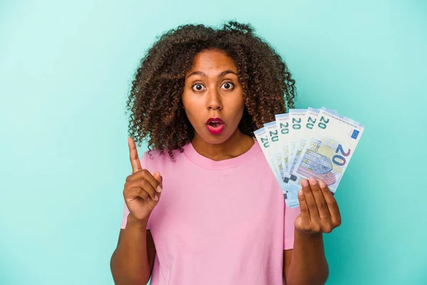 アフリカ系アメリカ人の若い女性が青い背景で孤立したユーロ紙幣を持っているアイデア インスピレーションの概念 — ストック写真