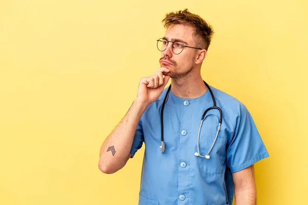 Jonge Verpleegster Blanke Man Geïsoleerd Gele Achtergrond Kijken Zijwaarts Met — Stockfoto