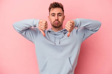 Pembe arka planda izole edilmiş genç beyaz bir adam hoş olmayan bir jest yapıyor. Anlaşmazlık konsepti.