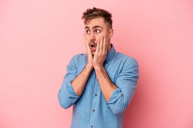 Pembe arka planda izole edilmiş genç beyaz adam korkmuş ve korkmuş..