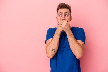 Pembe arka planda izole edilmiş genç beyaz bir adam. Düşünceli bir şekilde ağzıyla ağzını kapatan bir fotokopi odasına bakıyor..