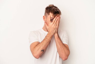 Beyaz arka planda izole edilmiş genç beyaz bir adam şüpheli ve şüpheci bir ifadeyle yana bakıyor..