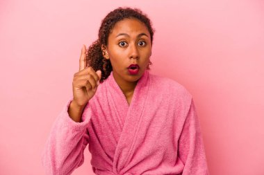 Pembe arka planda bornoz giyen Afro-Amerikalı genç bir kadının bir fikri var, ilham verici bir kavram..