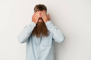 Beyaz arka planda uzun sakallı beyaz tenli genç beyaz adam elleriyle gözlerini kapatmaktan korkuyor..