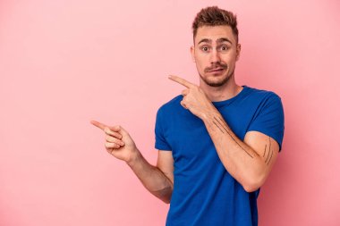 Pembe arka planda izole edilmiş genç beyaz adam işaret parmağıyla fotokopi alanını işaret ederek şok oldu..