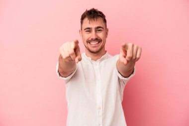 Pembe arka planda izole edilmiş genç beyaz adam. Önü işaret eden neşeli gülümsemeler..
