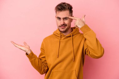 Pembe arka planda izole edilmiş genç beyaz adam işaret parmağıyla hayal kırıklığı jesti gösteriyor..