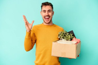 Genç beyaz adam mavi arka planda tek başına hareket ediyor. Hoş bir sürprizle karşılaşıyor. Heyecanlı ve el kaldırıyor..