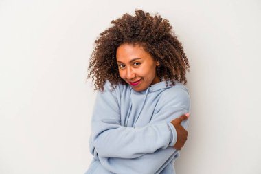 Beyaz arka planda izole edilmiş kıvırcık saçlı, gamsız gülümseyen ve mutlu genç Afrikalı Amerikalı kadın..