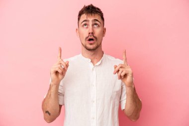 Pembe arka planda izole edilmiş beyaz bir adam ağzı açık bir şekilde üst tarafı işaret ediyor..