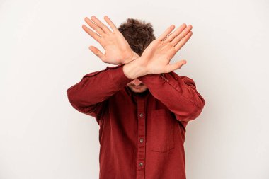 Beyaz arka planda izole edilmiş genç beyaz adam elleriyle ağzını kapatırken şok oldu..