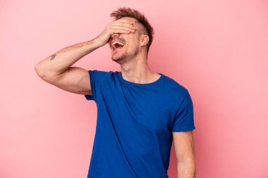 Pembe arka planda izole edilmiş genç beyaz adam ellerini başının üstünde tutarak neşeyle gülüyor. Mutluluk kavramı.