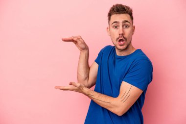 Pembe arka planda izole edilmiş genç beyaz adam elleri arasında bir fotokopi alanı tutuyor..