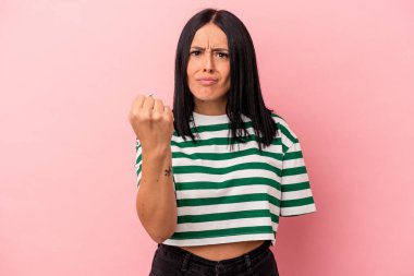 Tek kollu beyaz bir kadın pembe arka planda izole edilmiş yumruğunu kameraya gösteriyor, agresif bir yüz ifadesi var..