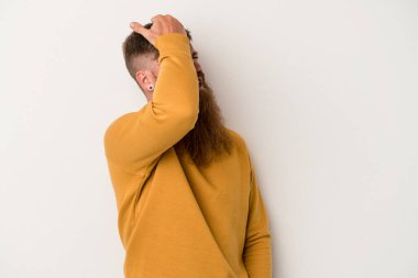 Beyaz arka planda uzun sakallı beyaz tenli genç beyaz adam bir şeyi unutuyor, alnına avuç içi ve gözlerini kapatarak tokat atıyor..