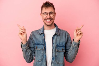 Pembe arka planda izole edilmiş genç beyaz adam farklı fotokopi alanlarını gösteriyor, birini seçiyor, parmaklarıyla gösteriyor..