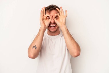 Beyaz arka planda izole edilmiş genç beyaz bir adam rahatlamış bir şeyin fotokopi odasına baktığını düşünüyor..