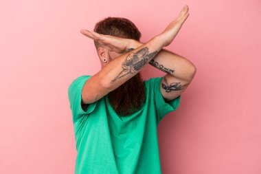 Uzun sakallı beyaz bir adam pembe arka planda izole edilmiş iki kolu çapraz tutuyor, inkar kavramı..