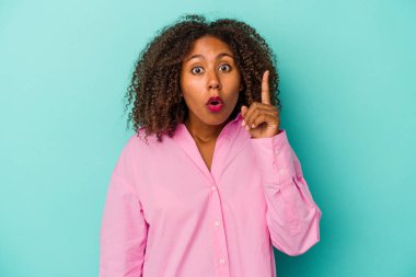 Mavi arka planda izole edilmiş kıvırcık saçlı Afro-Amerikalı genç bir kadın. Harika bir fikri var, yaratıcılık kavramı..