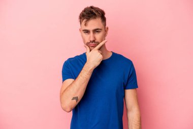 Pembe arka planda izole edilmiş genç beyaz adam bir strateji planlıyor, bir iş yolu düşünüyor..