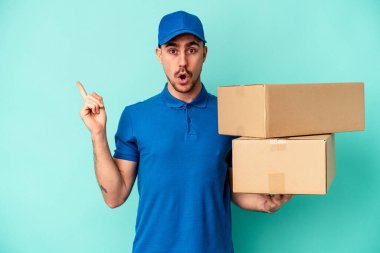Genç teslimatçı beyaz adam mavi arka planda izole edilmiş.