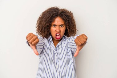 Beyaz arka planda izole edilmiş kıvırcık saçlı genç Afrikalı Amerikalı kadın baş parmağını aşağı gösteriyor ve hoşlanmadığını ifade ediyor..