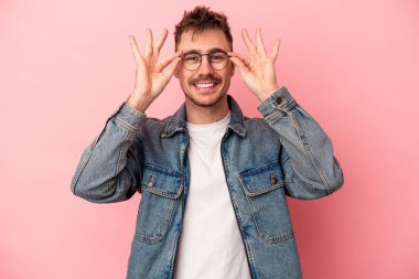 Pembe arka planda izole edilmiş genç beyaz adam gözlerinde sorun olmadığını gösteriyor.