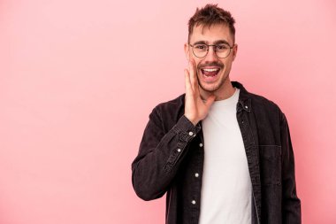 Pembe arka planda izole edilmiş genç beyaz adam yüksek sesle bağırıyor, gözleri açık ve elleri gergin tutuyor..
