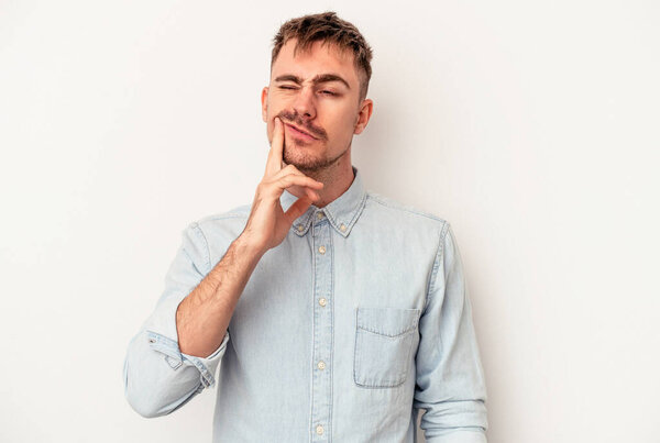 Молодой кавказский человек изолирован на белом фоне, сомневаясь между двумя вариантами.