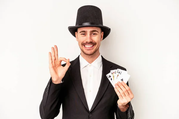 若いですCaucasianウィザード男保持Aマジックカード隔離上の白い背景陽気で自信を持ってショーOkジェスチャー — ストック写真