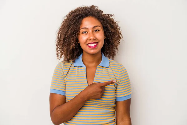 年轻的非洲裔美国女人 卷曲的头发被白色背景所隔离 面带微笑地指向一边 在空白的空间里表现出某种东西 — 图库照片